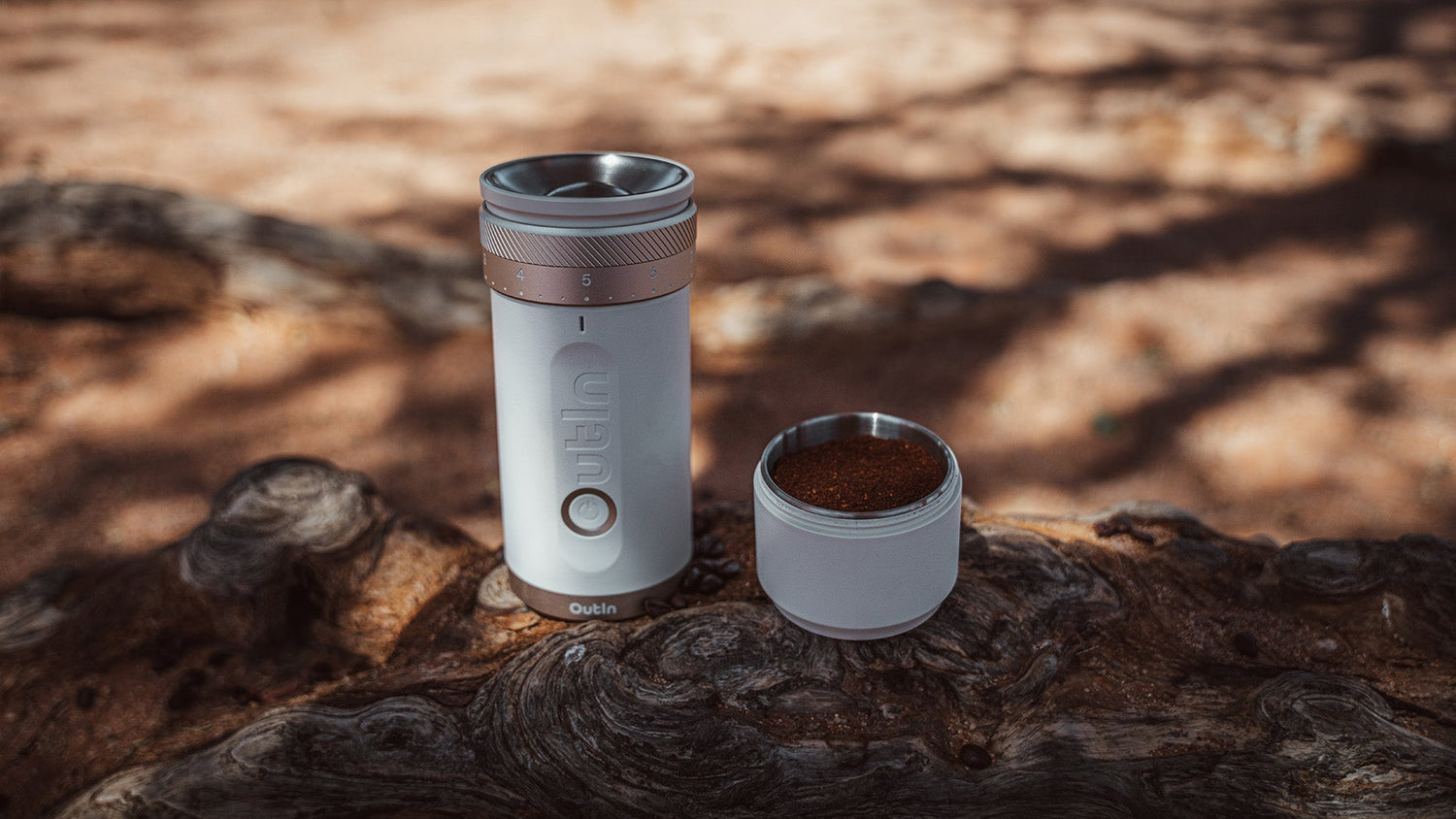 Hand pouring coffee beans into top of Outin manual grinder, demonstrating first step in grinding process with visible coarseness adjustment settings for precise control over grind size
